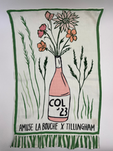 Load image into Gallery viewer, Tea towel with a bottle and flowers design, featuring &#39;COL &#39;23&#39; and &#39;Amuse La Bouche x Tillingham&#39;.